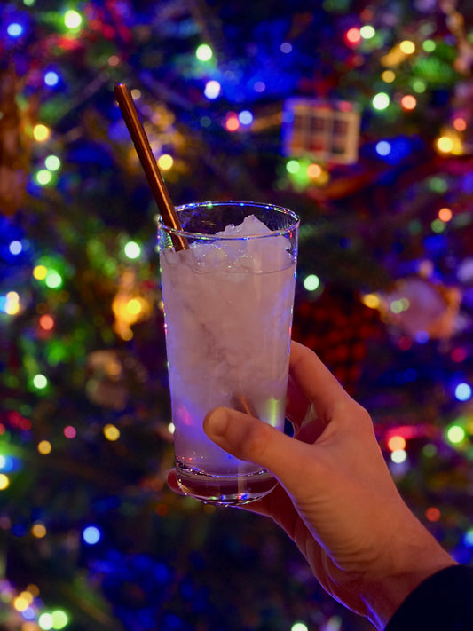 Snowjito in a glass in front of a decorated tree