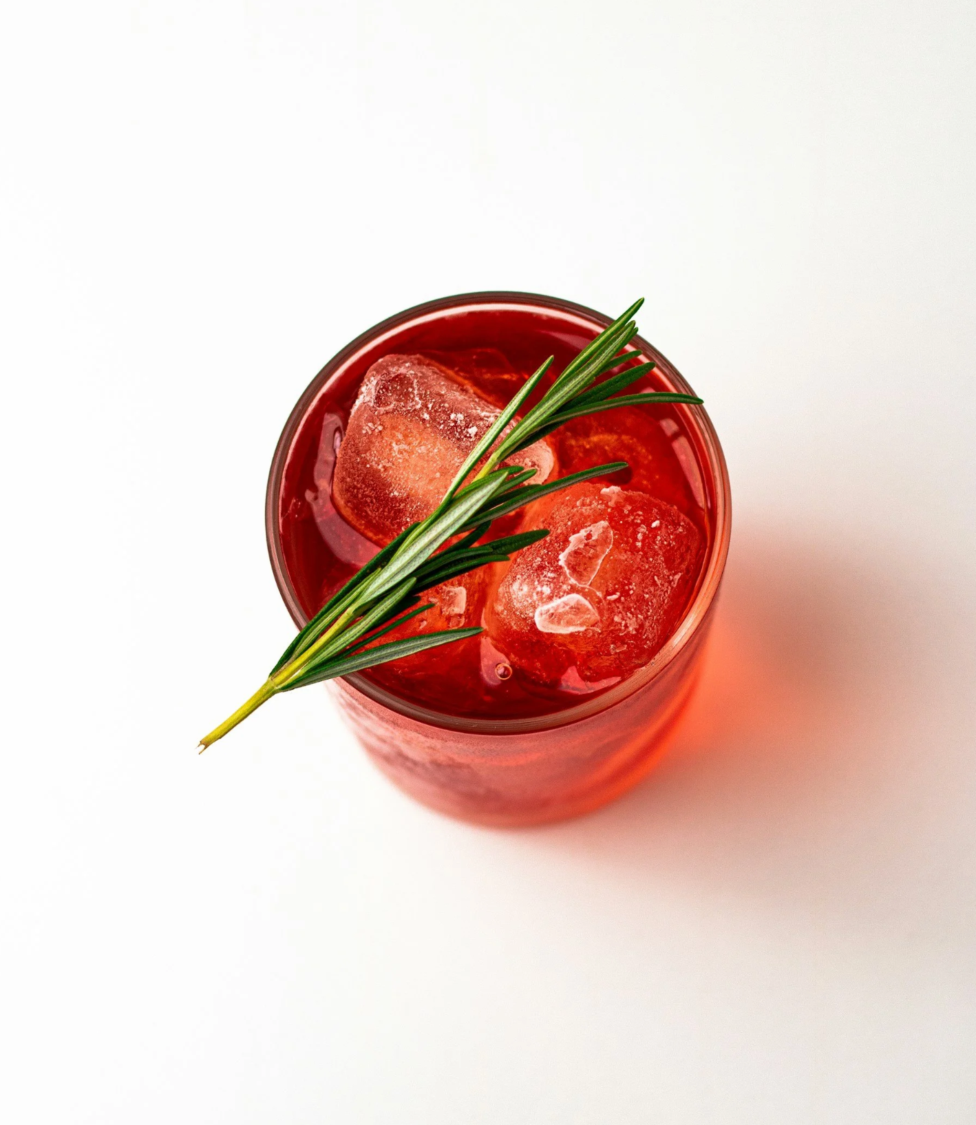 Our Cherry Negroni over ice, viewed from the top, with a rosemary garnish