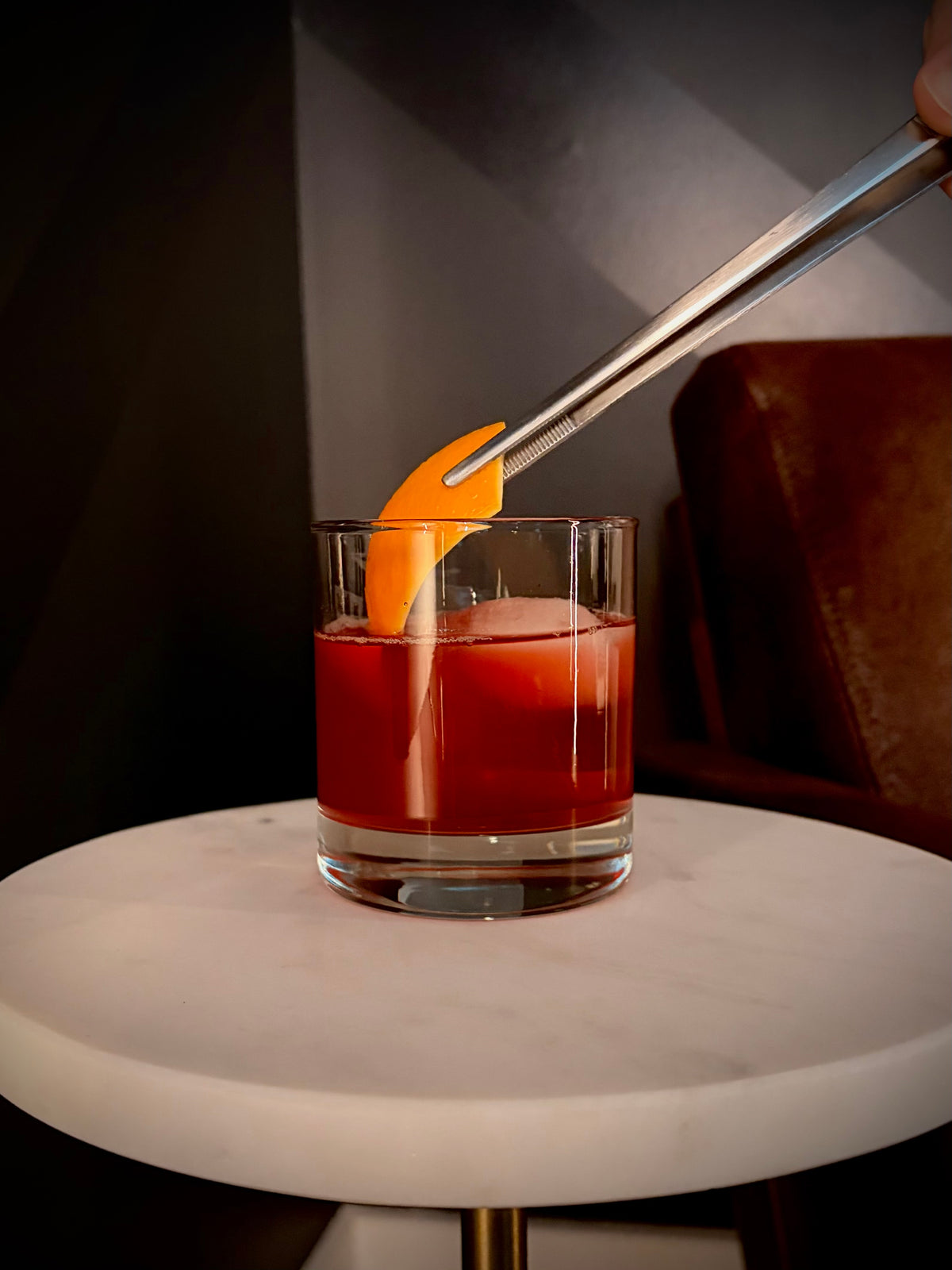 Non-alcoholic cherry negroni over ice in a rocks glass with an orange peel garnish