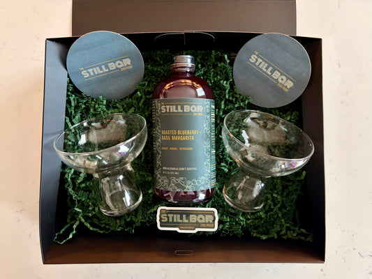Gift box including a bottle of Roasted Blueberry + Basil margarita with glassware and logo items